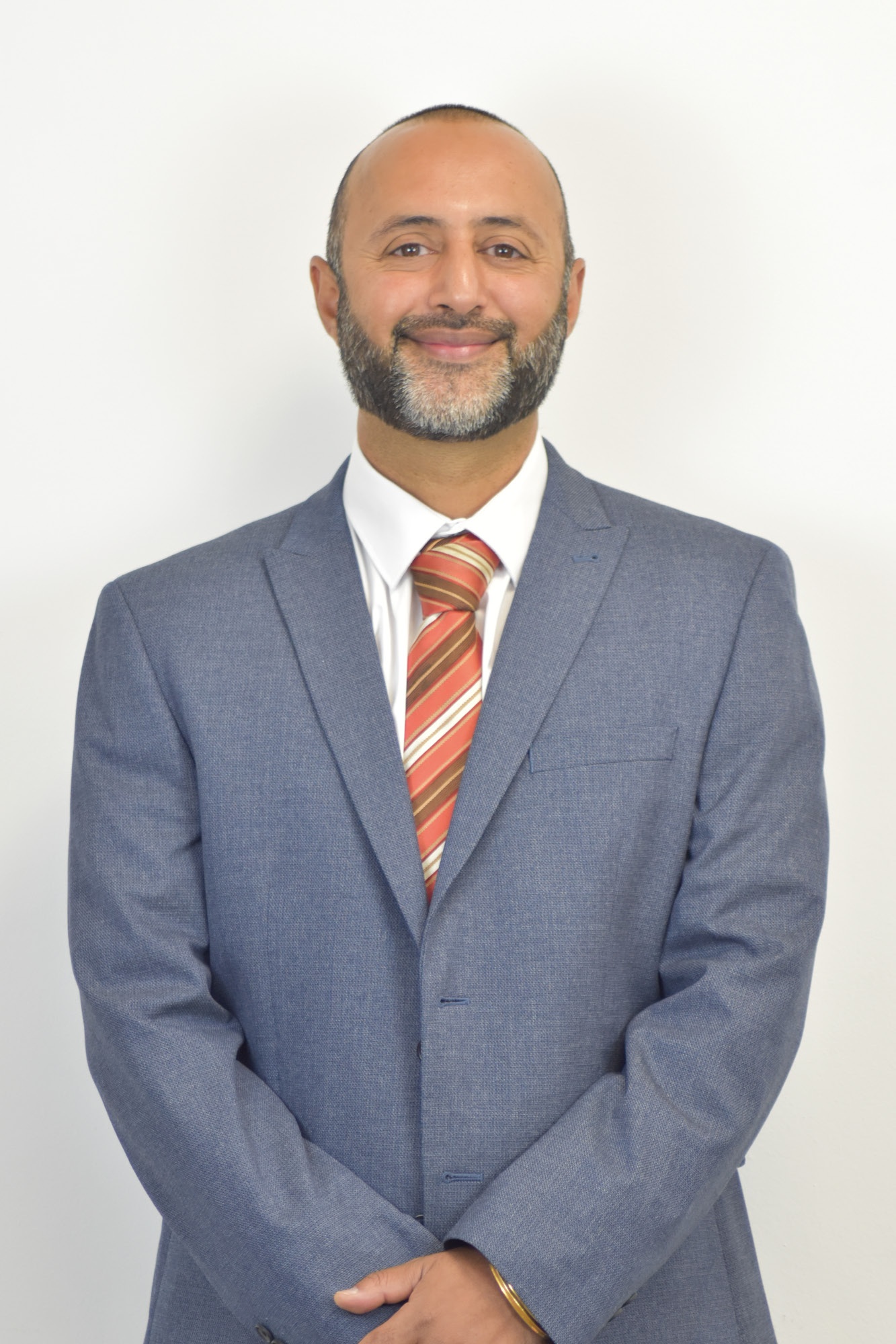 Mr Johal, the Head of School, smiles at the camera.
